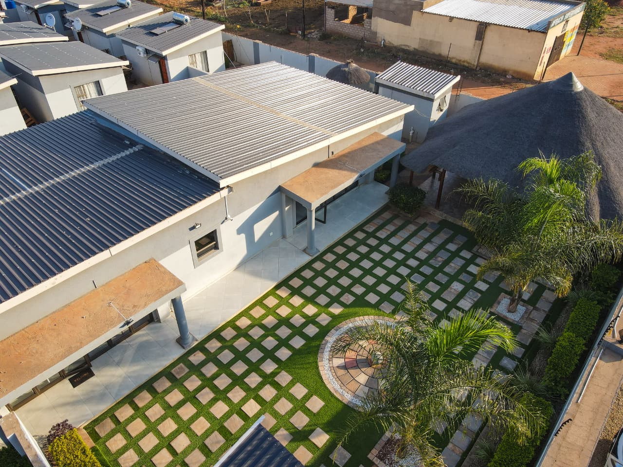 Aerial view of The Elephant Lodge grounds with gardens and thatched gazebo