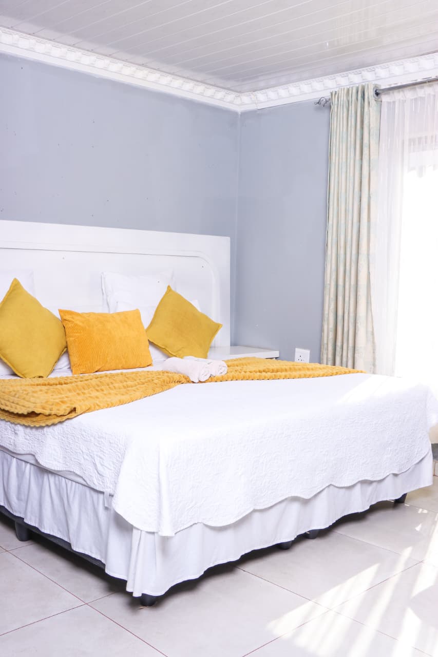 Double room with white and mustard bedding at The Elephant Lodge